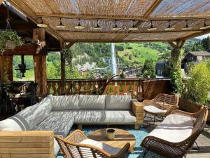 un patio con sofá y sillas bajo una pérgola en La Ferme, en La Clusaz