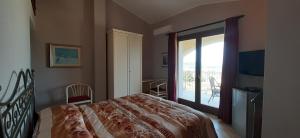 ヴィッラプッツにあるAffittacamere Belvedere La Peoniaのベッドルーム1室(ベッド1台付)、バルコニーへのドアが備わります。