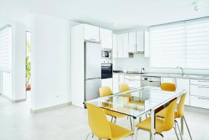 a kitchen with a glass table and yellow chairs at VILA CARLA - 3BDR + 3BATH in Amarilla Golf in San Miguel de Abona