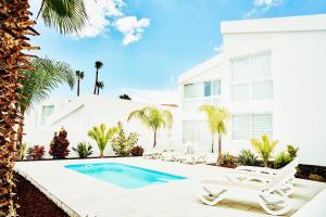 a white house with a swimming pool and lounge chairs at VILA CARLA - 3BDR + 3BATH in Amarilla Golf in San Miguel de Abona