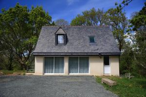 a white house with a gray roof and a driveway at Aux Arbres Chanteurs in Ploulech