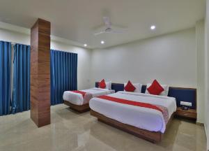 two beds in a bedroom with blue drapes at Hotel Kuber in Dwarka +18 photos