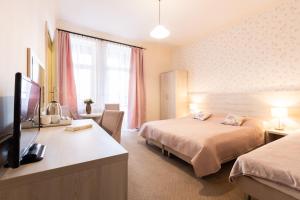 a hotel room with two beds and a flat screen tv at Villa Elizabeth in Kudowa-Zdrój