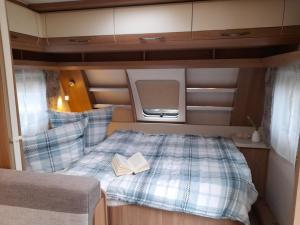 um pequeno quarto com uma cama com um livro em Wohnwagen auf Privatgrundstück auf der Halbinsel Mönchgut/Rügen em Middelhagen