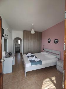 a bedroom with a white bed and a pink wall at Marianthi Studios in Áno Meriá