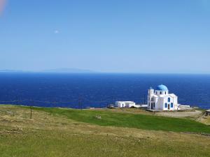 un bâtiment blanc sur une colline avec l'océan en arrière-plan dans l'établissement Marianthi Studios, à Áno Meriá