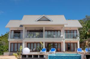 a house with a swimming pool and blue chairs at Terrasse Sur Lazio in Anse Lazio