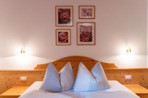 um quarto com uma cama com lençóis brancos e almofadas em Pension-Appartement Mitterhofer em Schenna
