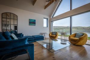 a living room with blue furniture and large windows at Tides Uig Isle of Skye in Uig