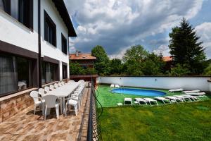 a patio with a table and chairs and a swimming pool at КЪЩА ЗА ГОСТИ ХАРМОНИ in Shiroki Dol