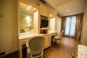 マリーノにあるLH Hotel Domus Caesariのデスク、テレビ、椅子が備わるホテルルームです。