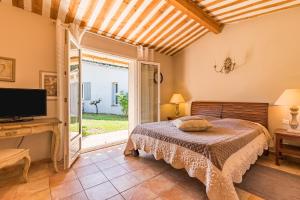 ヴェゾン・ラ・ロメーヌにあるJade En Provenceのベッドルーム(ベッド1台、テレビ、窓付)