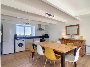 a dining room with a wooden table and yellow chairs at Maison 6 pers proche centre ville in Bréhal