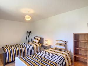 2 camas en una habitación con paredes blancas en Maison 6 pers proche centre ville, en Bréhal