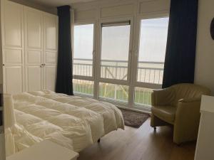Schlafzimmer mit einem Bett, einem Stuhl und Fenstern in der Unterkunft Hello Zeeland - Appartement Port Scaldis 19-012 in Breskens