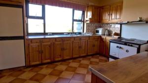 a kitchen with wooden cabinets and a large window at The Bungalow in Doonbeg