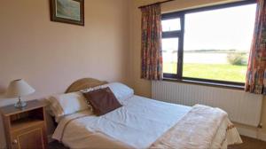 1 dormitorio con cama y ventana en The Bungalow en Doonbeg