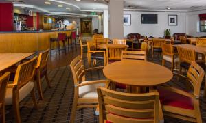 a restaurant with wooden tables and chairs and a bar at Holiday Inn Express Swansea East by IHG in Swansea
