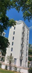 un gran edificio blanco con balcones. en Hotel Kaligrosh, en Sutomore