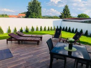 un patio con 2 bancos, mesa y sillas en Vila Sky Kragujevac, en Kragujevac