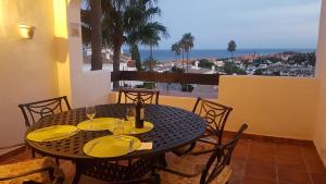 una mesa negra con platos amarillos y copas de vino en Modern Duquesa 2 Bed Outstanding view of sea golf en Manilva