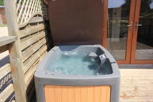 a hot tub sitting on a deck with a bench at Barker Stakes Farm in Pickering