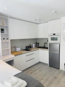 a kitchen with white cabinets and stainless steel appliances at CP Top floor luxury studio in Gibraltar
