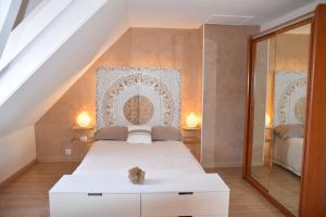 um quarto com uma cama branca e um espelho em Chambres d’Hôtes Les Rougemonts em Champguyon