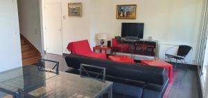 - un salon avec un canapé noir et des fauteuils rouges dans l'établissement La Regina, à Trouville-sur-Mer