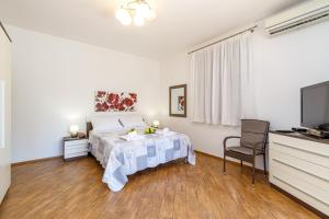 a white bedroom with a bed and a television at Apartments Kiki 150 METERS TO THE BEACH in Banjole