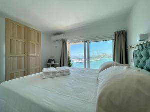 Schlafzimmer mit einem großen weißen Bett und einem großen Fenster in der Unterkunft Eos Sea View Apartments in Syrakus