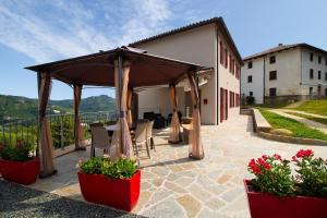 a patio with a gazebo and chairs and flowers at Casa Nonna Ida - Vacanze in Langa in Santo Stefano Belbo