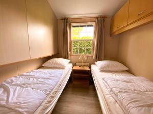2 camas en una habitación pequeña con ventana en Hello Zeeland - Vakantiehuis Paarlhof 51, en Groede