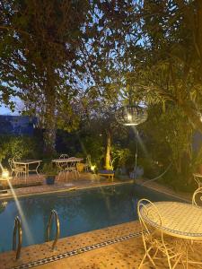 a swimming pool with tables and chairs and a table and a table at Riad Jean Claude in Fez