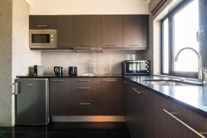 a kitchen with brown cabinets and a stainless steel refrigerator at Topazio Vibe Beach Hotel & Apartments - Adults Friendly in Albufeira
