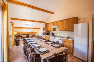 a kitchen with a long table with chairs and a refrigerator at 130m2 ,5 chambres, trés bien situé in Les Deux Alpes