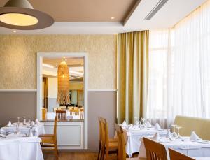 a restaurant with white tables and chairs and a mirror at PortoBay Falesia in Albufeira