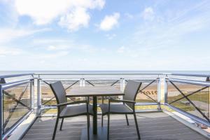 a table and chairs on a balcony with a view of the beach at DE TRINTEL met zeezicht in Egmond aan Zee