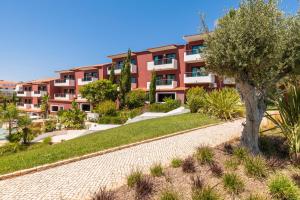 an apartment building with a tree in front of it at Topazio Vibe Beach Hotel & Apartments - Adults Friendly in Albufeira
