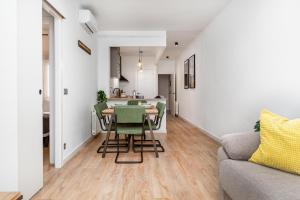 a living room with a table and chairs and a kitchen at Fridays Flats Simply Stunning - Hidden Gem, Heart Of Poble Sec in Barcelona