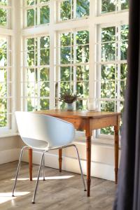 uma cadeira branca sentada numa mesa de madeira em frente a uma janela em Taunton Manor em Pietermaritzburg