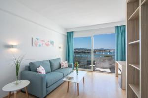 a living room with a blue couch and a large window at Smy Vistamar Portocolom in Portocolom