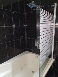 a black tiled bathroom with a tub and a shower at Parque das Amendoeiras in Vilamoura