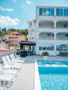 a building with white chairs and a swimming pool at Apartments Gjenashaj in Ulcinj