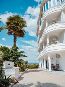 a large white building with a palm tree in the background at Apartments Gjenashaj in Ulcinj