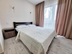 a bedroom with a bed and a large window at REEF Hotel in Koblevo