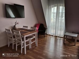 a dining room table with chairs and a tv on the wall at Apartament 4 Żagle in Giżycko