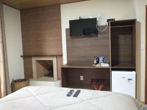 um quarto com uma cama e uma televisão na parede em Chalés do Pardal em Viscode de Mauá