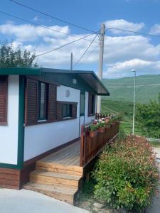 una casa con una terraza de madera con flores. en Dal Rosso, en San Floriano del Cóllio