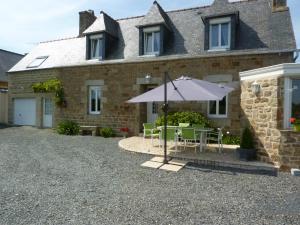 a house with a table and an umbrella in front of it at La Kerandière in Tonquédec +29 photos